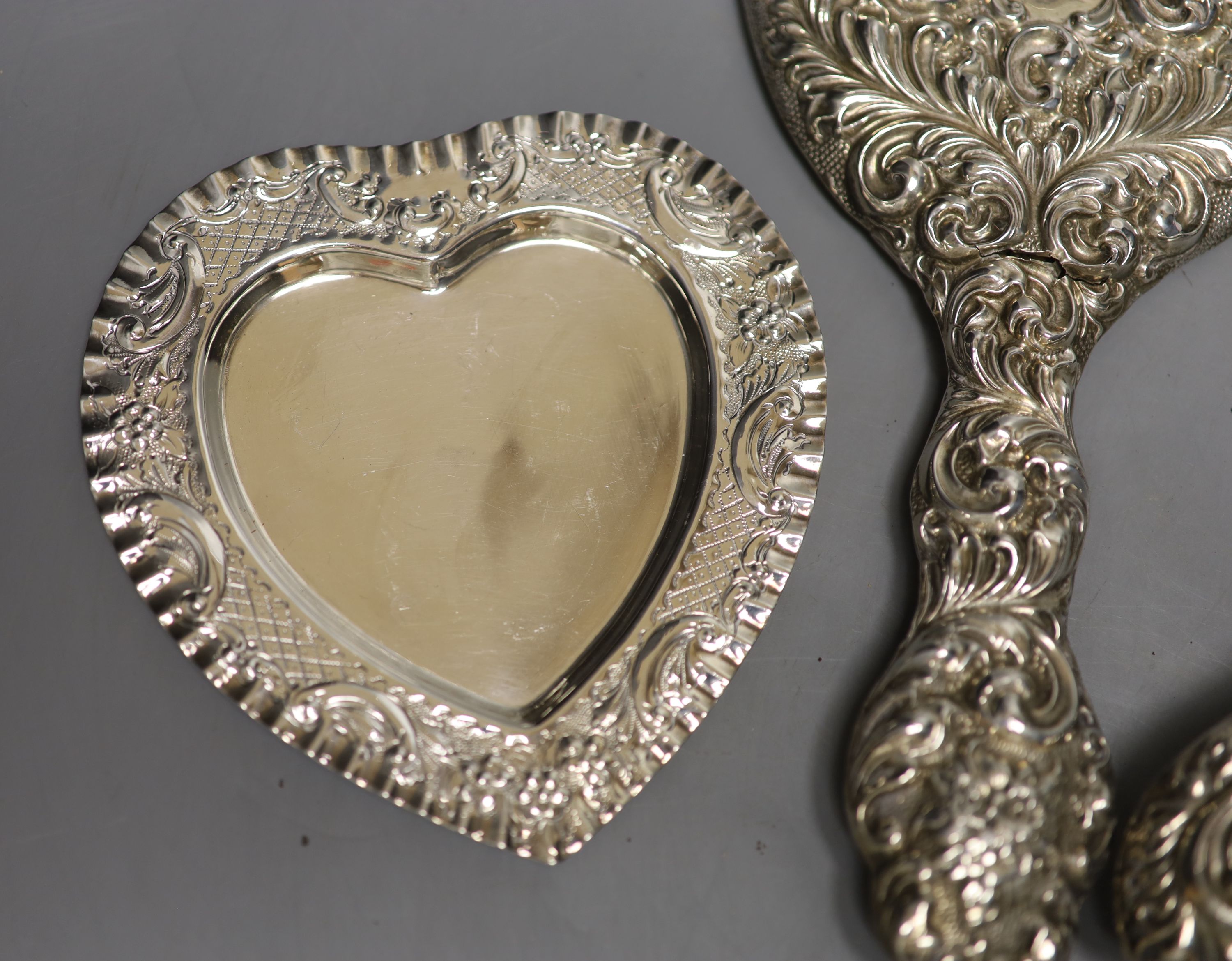 A silver cigarette case, a late Victorian silver heart shaped dish, a silver hand mirror and brush.